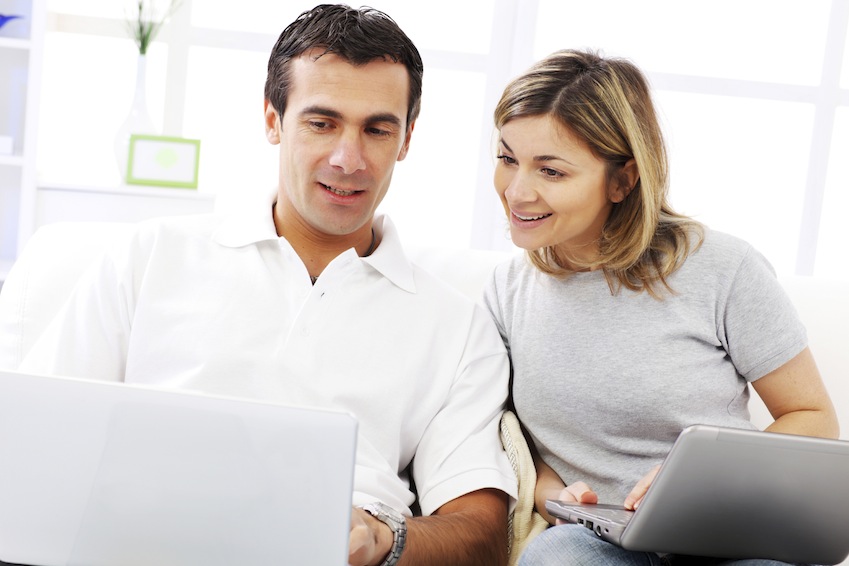 Couple using a laptop computer, sitting at home.